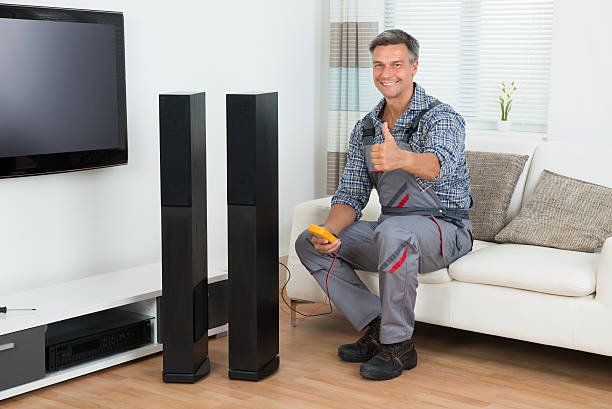 Full length of technician checking TV speaker with multimeter at home